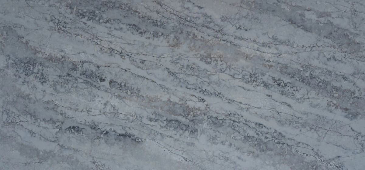 Witness our Atlantis Azul quartz slab features a stunning interplay of deep blues and subtle greys, reminiscent of the ocean’s depths. Its intricate veining creates a textured appearance evoking the timeless beauty of natural quartzite.